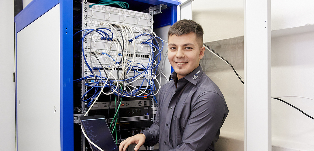 Mann steht vor einem IT Serverraum
