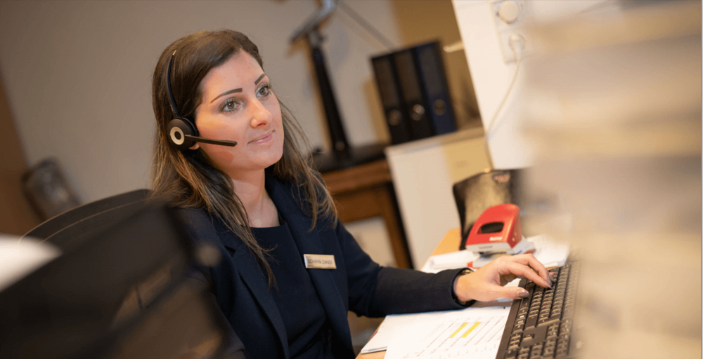 Mitarbeiterin mit Headset sitzt im Büro des Parkhotel Pörtschach